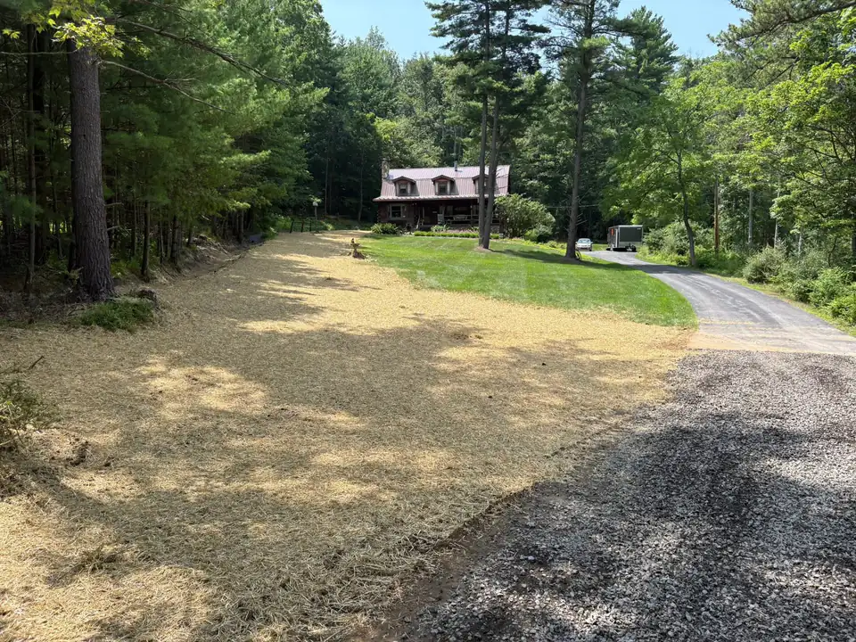 Residential driveway with prepared base material and house among trees