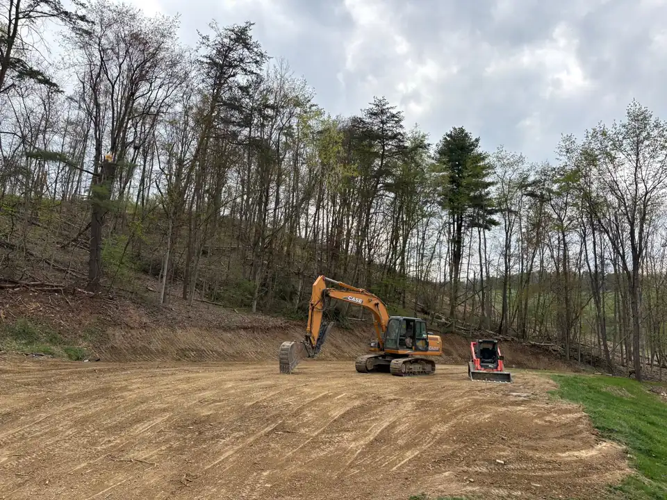 Two excavators working on cleared hillside with bare earth