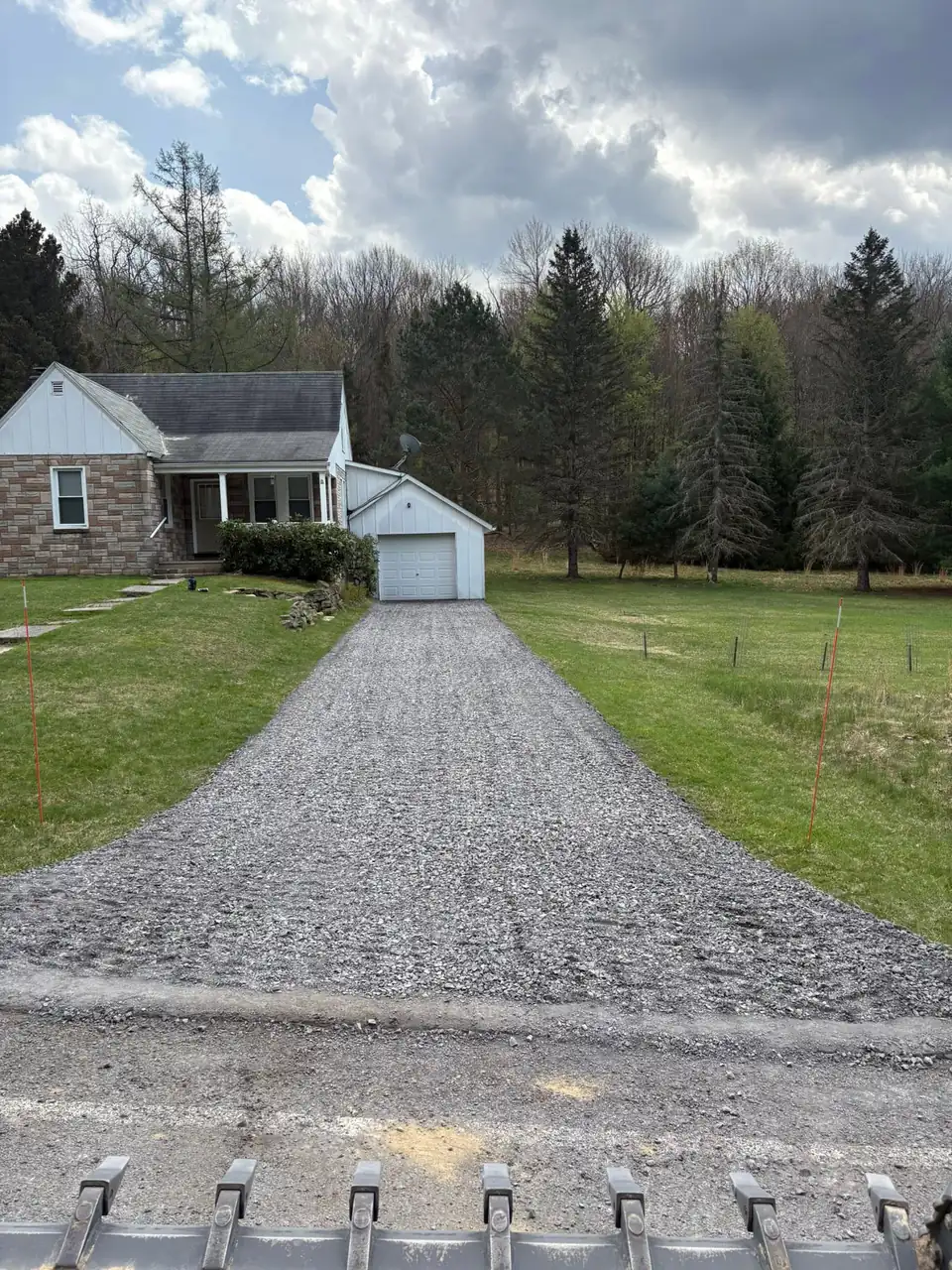 Fresh gravel driveway leading to a white house and garage