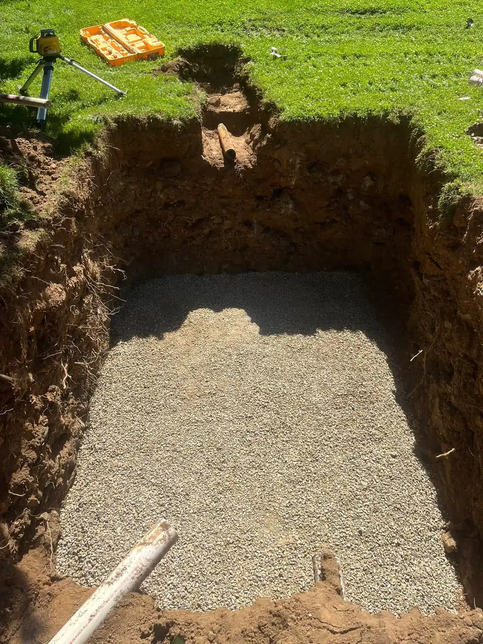 Prepared trench with gravel foundation and deep dirt walls.