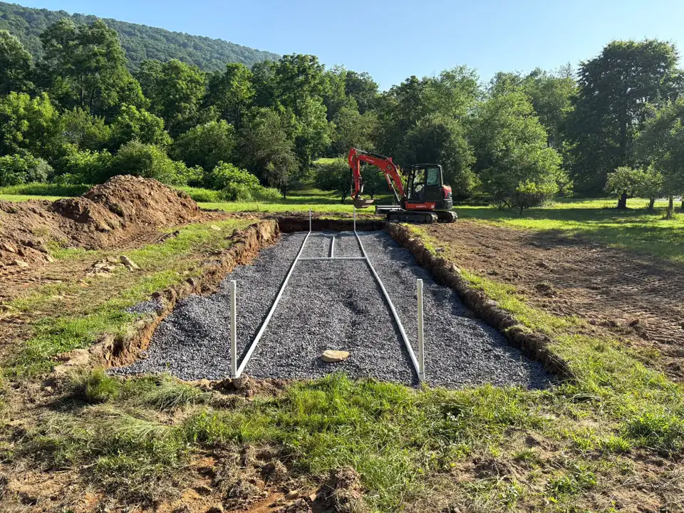 Excavator and gravel trench in open field