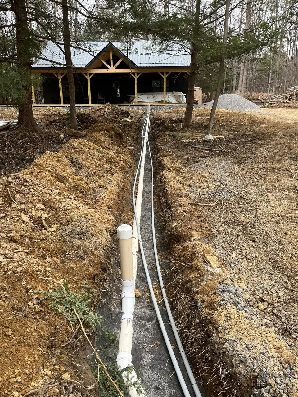 Trench with white pipes leading to a house