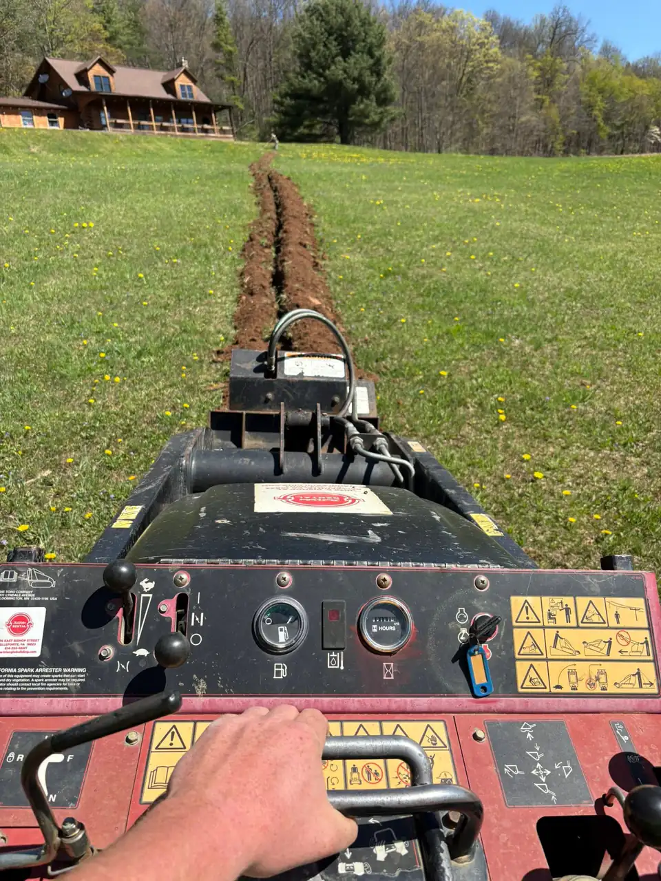 Trenching machine cutting trench in lawn