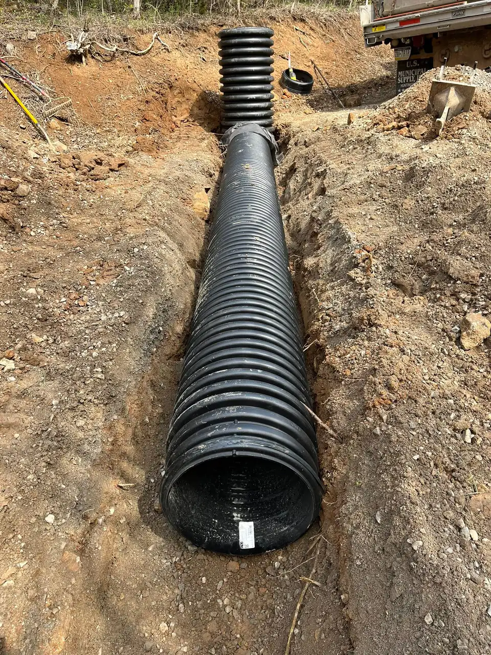 Large black corrugated pipe laid in an open trench