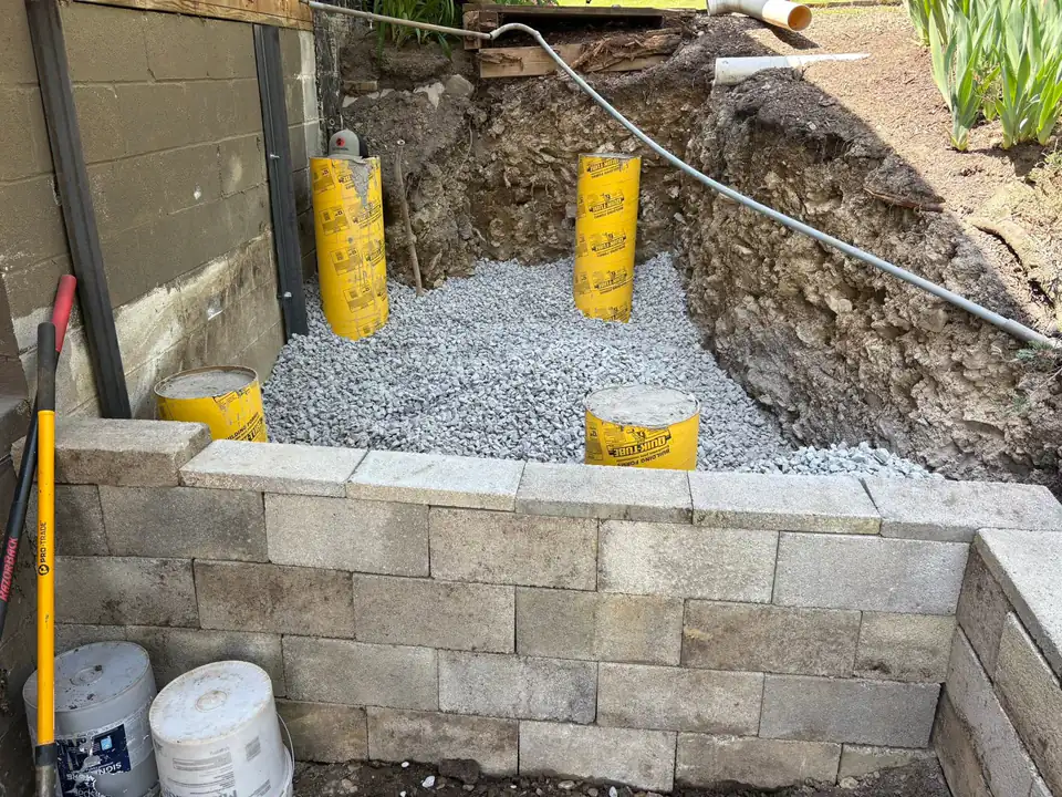 Gravel pit with yellow concrete form tubes and block retaining wall.